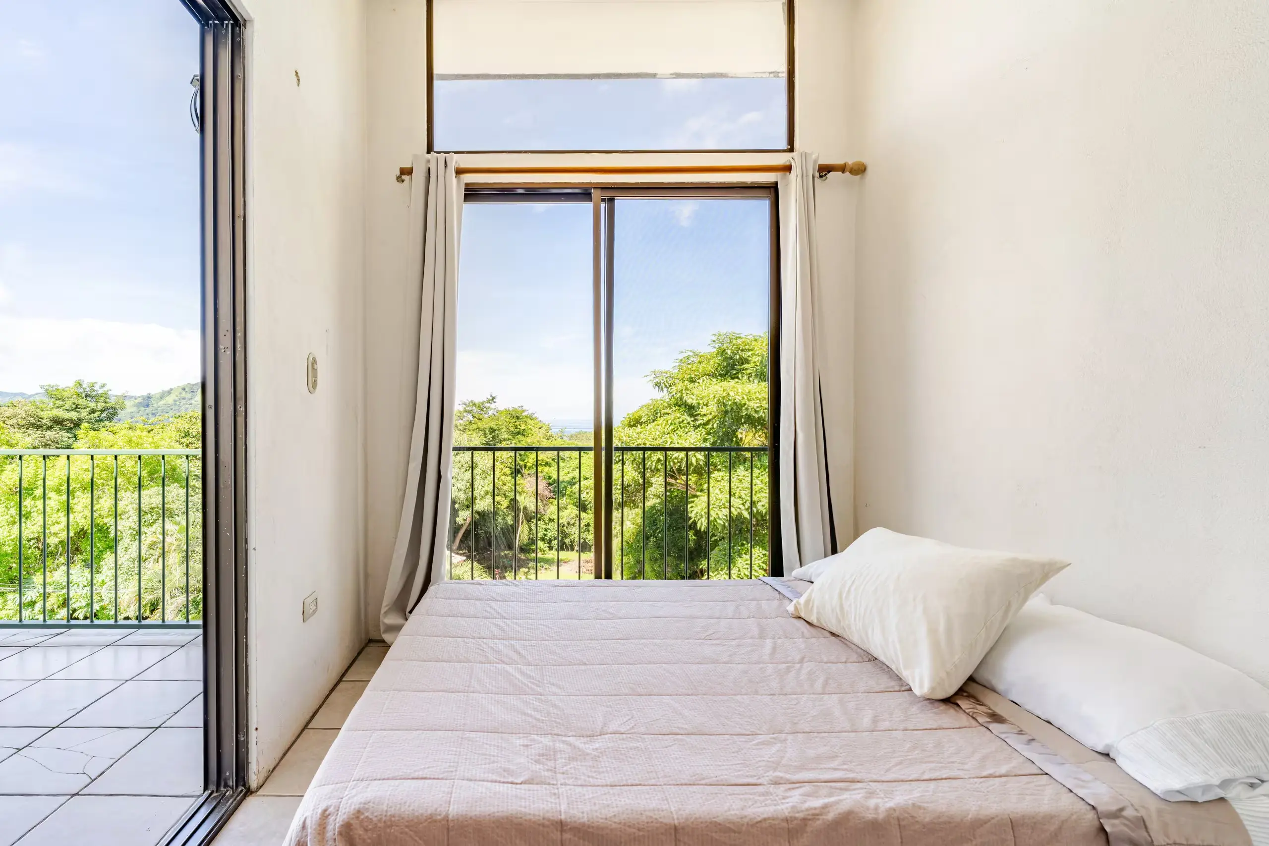 Bright top-floor bedroom with ocean and garden views — a peaceful space to wake up to the sounds of nature.