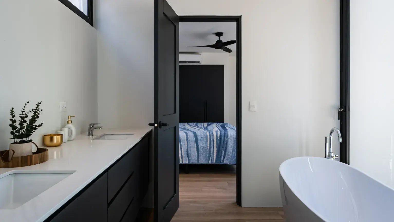 The luxurious primary bath features a freestanding soaking tub, sleek double vanity, and a view into the spacious master suite.